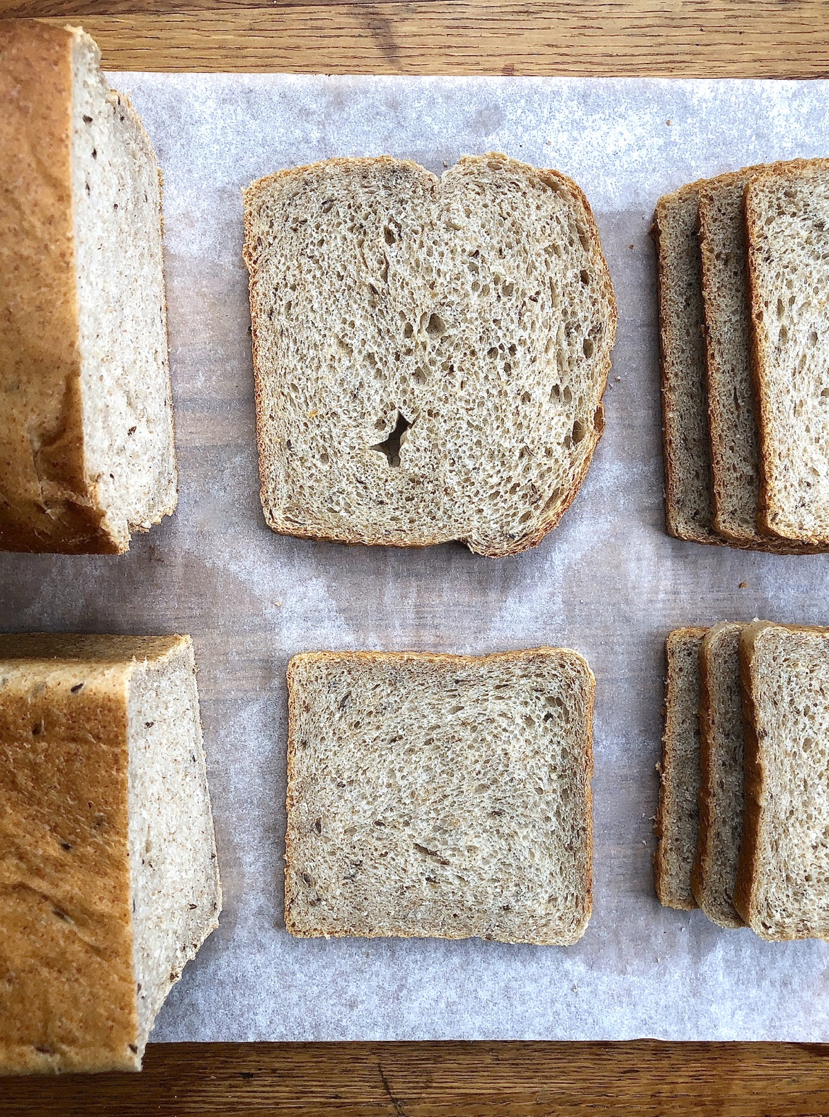 Slices of rye bread from two different pans, side by side on a cutting board, for shape comparison
