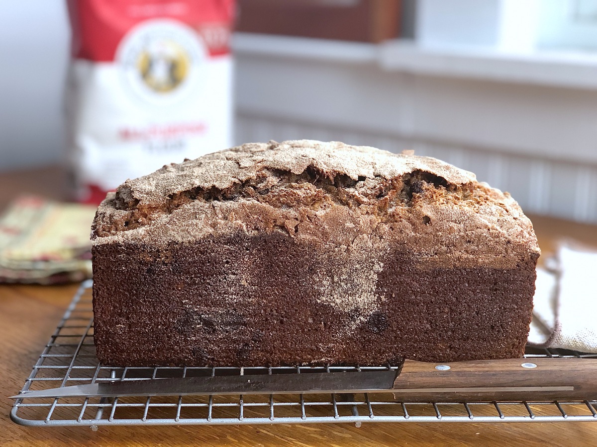 Loaf of whole grain banana bread on a cooling rack.