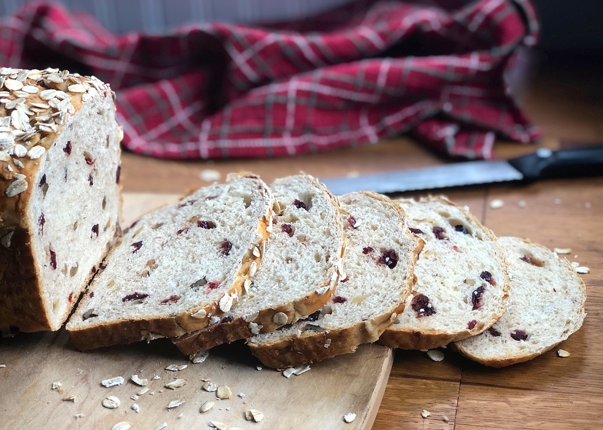 Oatmeal bread with dried cranberries and walnuts, sliced on a cutting board