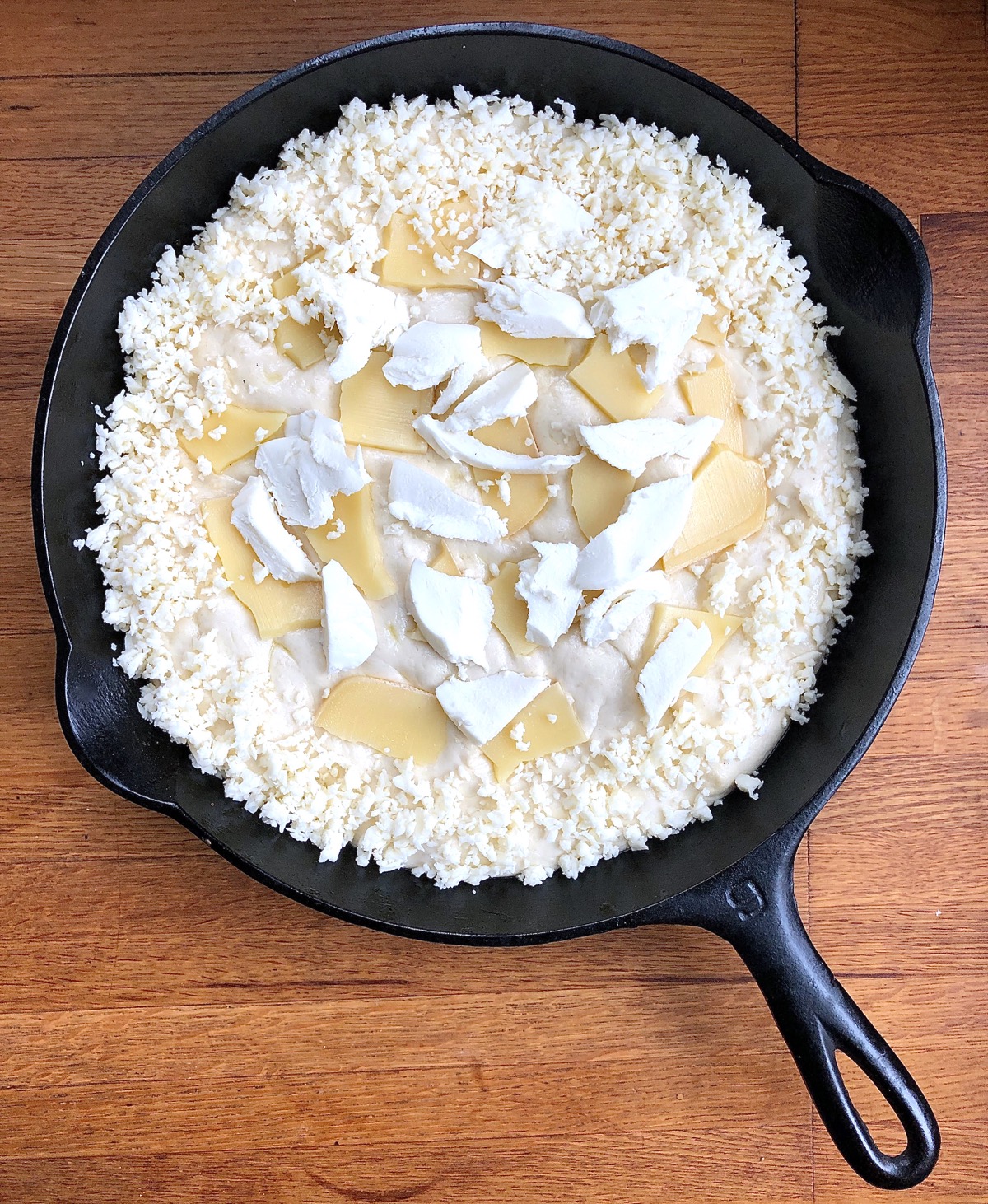 Pizza in a cast iron pan, topped and ready to bake.