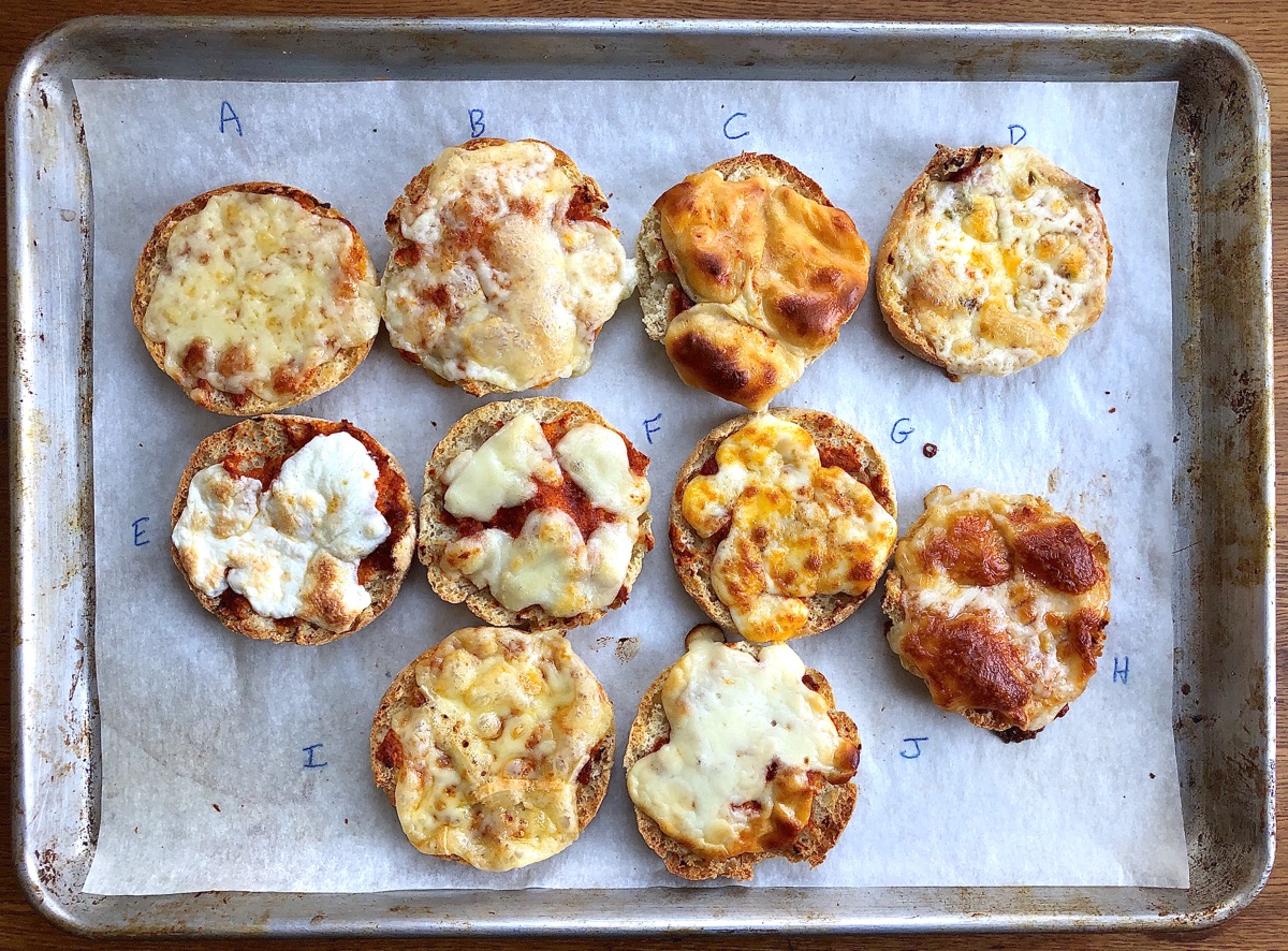 10 English muffin halves topped with sauce and different cheeses, baked until cheeses have melted.