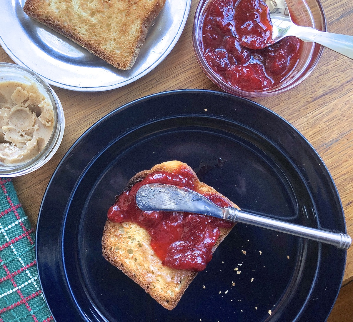 Toast on a plate, spread with butter and strawberry jam.