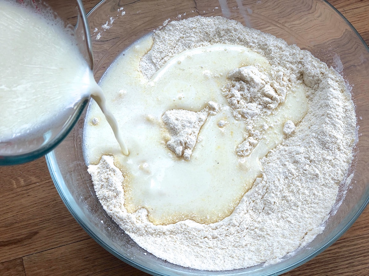 Pouring liquid ingredients into a bowl of dry ingredients to make cornbread