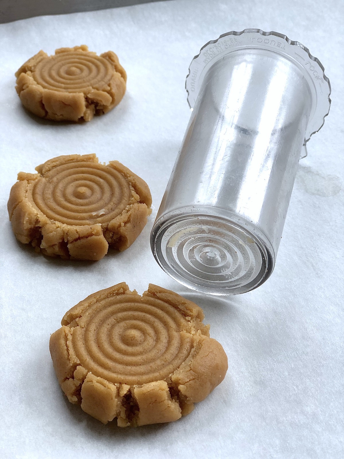 Puher from a food processor being used to imprint a design on the top of balls of shortbread dough.