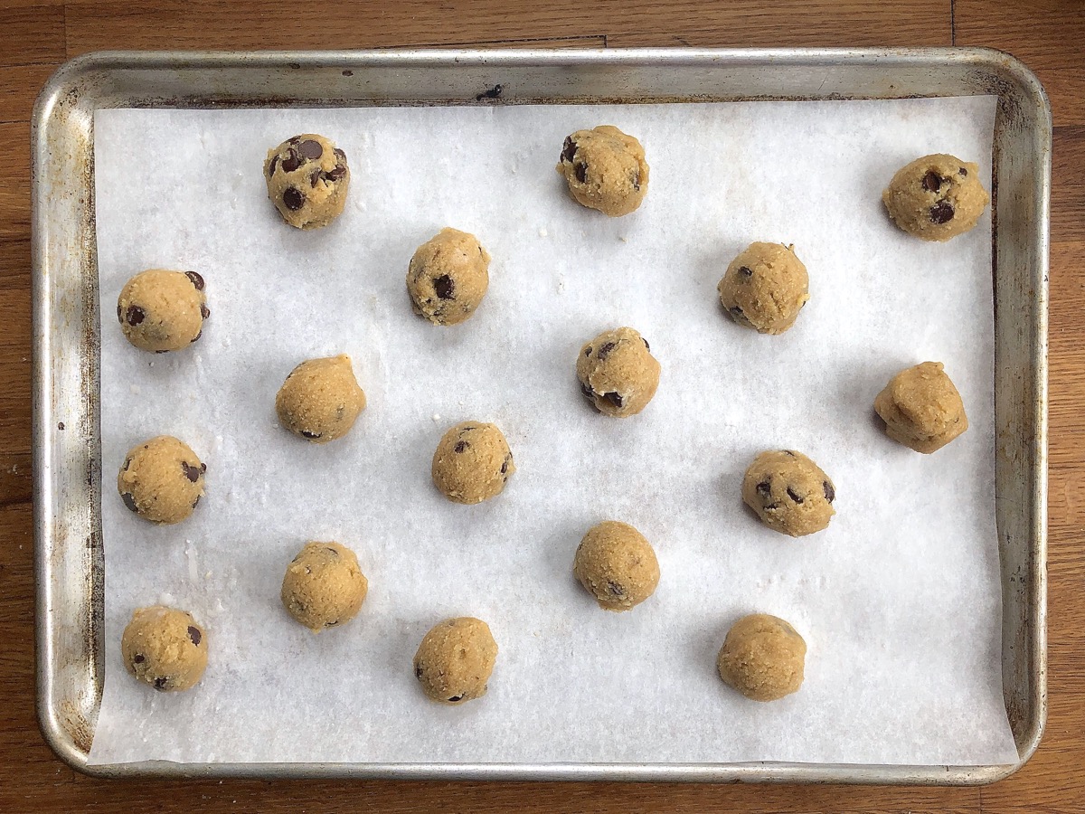 Dough for Gluten-Free Almond Flour Chocolate Chip Cookies scooped into balls on a parchment-lined baking sheet.
