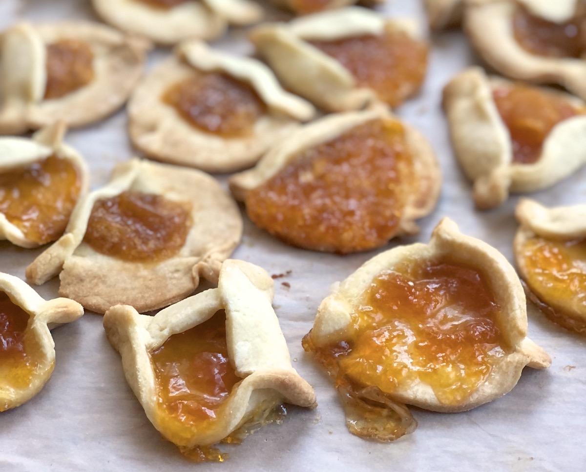 Misshapen hamantaschen cookies on a baking sheet.