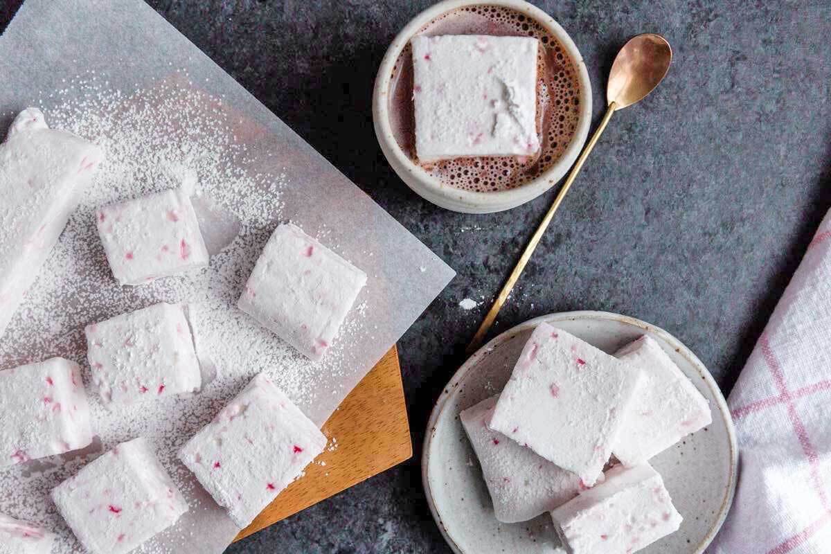 Peppermint marshmallows cut in blocks, some on a plate, some on a board, one in a cup of hot cocoa.