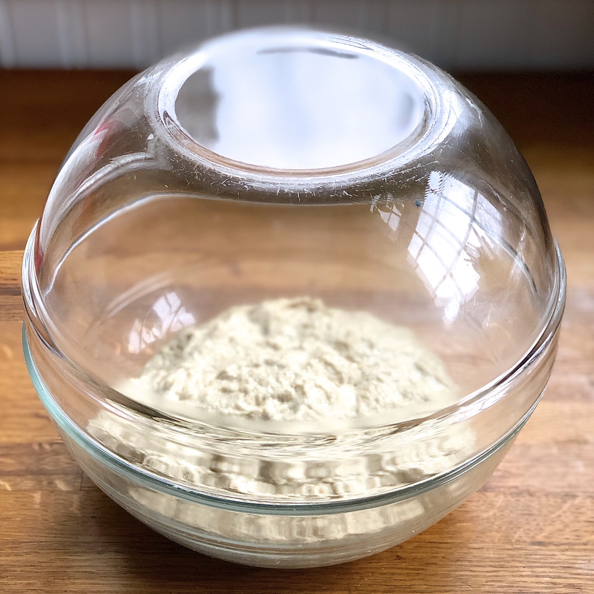 A preferment for Greek Olive and Onion Bread in a glass bowl, ready to rise overnight