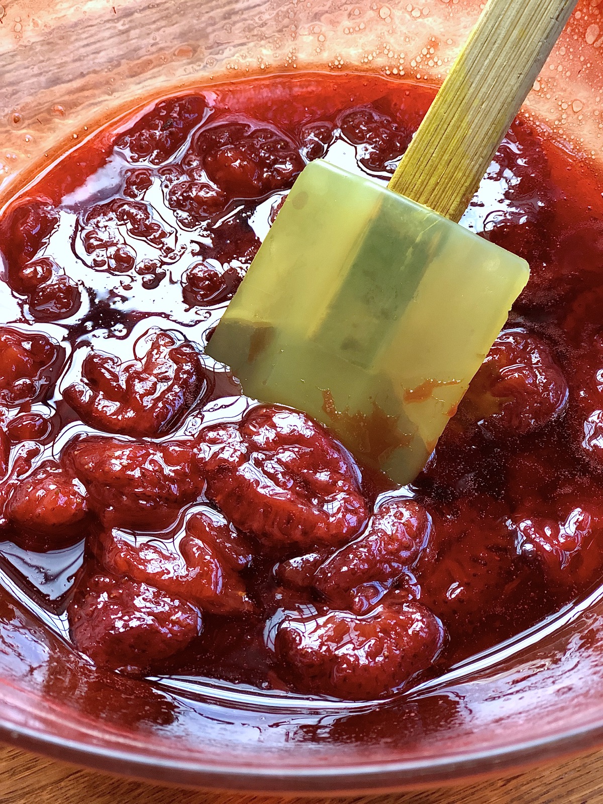 Bowl of cut strawberries and sugar after 10 minutes in the microwave — looking syrupy.