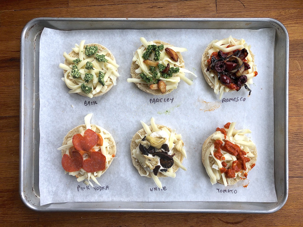 Testing six different sauces on English muffin halves; all lined up on a baking sheet ready to go into the oven.