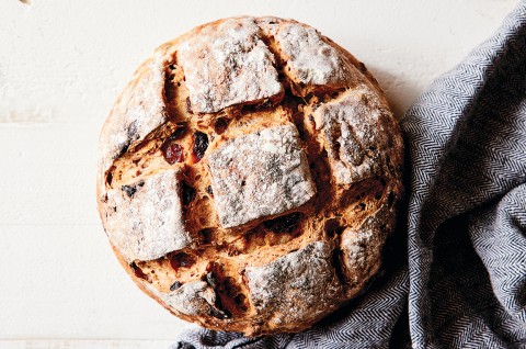 An artisan fruit bread with a crusty exterior and checkerboard pattern scored into the top.  - select to zoom