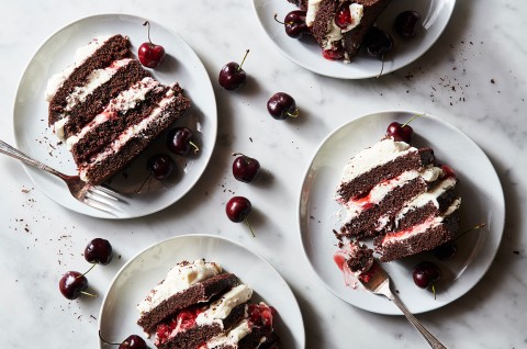 Slice of Black Forest Cake surrounded by fresh cherries, ready to be served - select to zoom