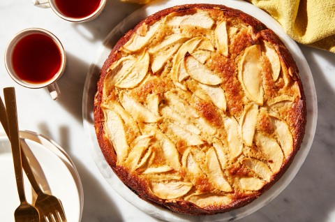 A freshly baked Mostly Apples Apple Cake next to two cups of tea and forks - select to zoom