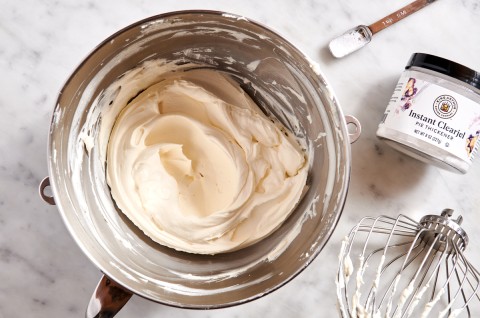 Stand mixer bowl of whipped cream next to Instant Clearjel