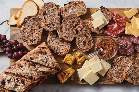An overhead photo of a loaf artisan fruit bread that has been sliced, showing off the fruit-studded interior. - select to zoom
