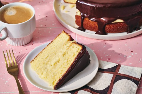 A slice of Boston Cream Pie on a plate, filled with vanilla pastry cream and topped with chocolate ganache. - select to zoom