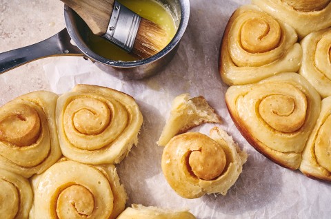A close up overhead photo of Buttery Sourdough Buns baked close together in rounds pans, one bun has been pulled away to show the soft, flaky interior texture.  - select to zoom