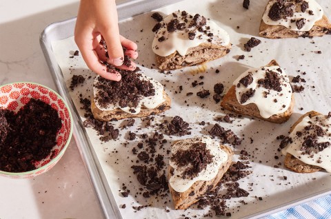 Glazed Cookies-and-Cream Scones being topped with cookie crumbles - select to zoom