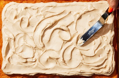 Silky frosting being applied to a cake with an offset spatula