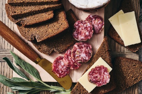 Classic Pumpernickel Bread sliced on a cutting board with meat and cheese - select to zoom