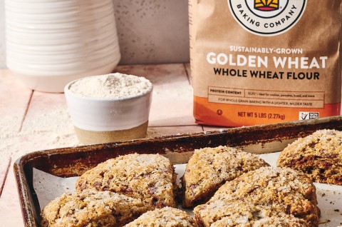 Cinnamon Whole Wheat Scones on a baking sheet with a cup of coffee - select to zoom