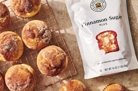 Cinnamon-Sugar Doughnut Muffins on a cooling rack with bag of cinnamon sugar - select to zoom