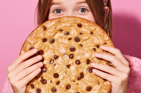 A young girl hiding behind a Chocolate Chip Skillet Cookie - select to zoom