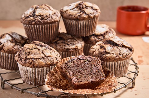 Chocolate Zucchini Muffins on a cooling rack with one halved - select to zoom