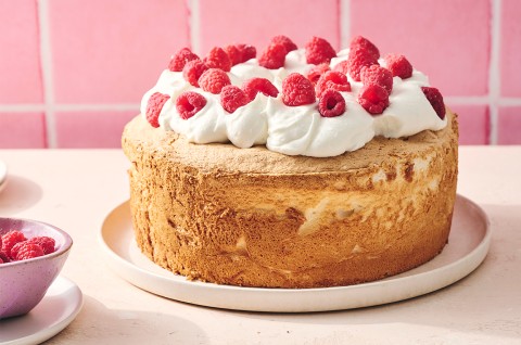 A compelte Gluten-Free Angel Food Cake topped with whipped cream and raspberries - select to zoom
