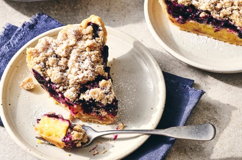 A slice of Lemon-Blueberry Streusel Pie on a plate with a piece taken out on a fork - select to zoom