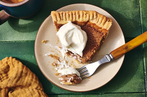 A fork topped with a small bite of apple pie along with the rest of the slice on a plate seen from above. - select to zoom