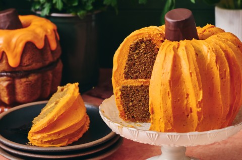A sliced pumpkin shaped bundt cake showing layers of dark cake and orange frosting. - select to zoom