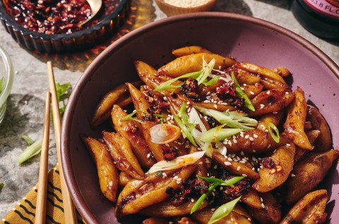 A purple tinted bowl filled with hand cut noodles dressed with umami sauce. - select to zoom