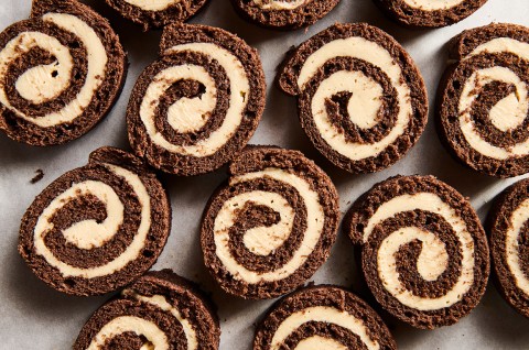 Sliced pinwheels of chocolate cake filled with Cookie Butter Whipped Ganache all laying side by side on a sheet tray.
