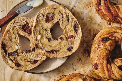 A sliced and buttered Cinnamon Raisin Bagel on a plate. - select to zoom