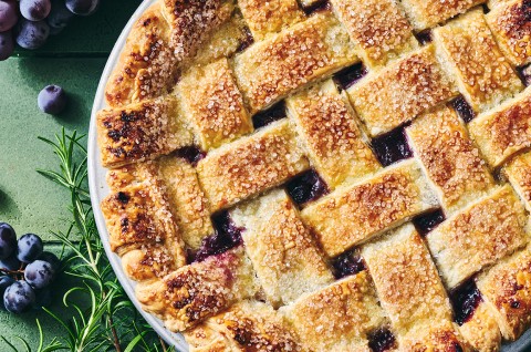 Concord Grape Pie photographed from above showing a lovely woven pie crust on top with brown hues and coarse sugar. - select to zoom