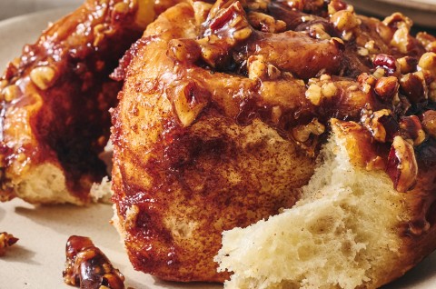 Detailed photograph of a dark brown sticky bun peeled apart showing a sweet and perfectly baked interior. - select to zoom
