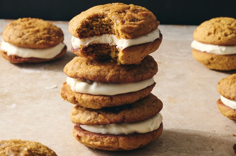 Pumpkin Whoopie Pies photographed in a stack on a counter showing the layers of pumpkin cookie and creamy filling. - select to zoom