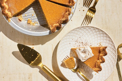 A slice of Smooth and Spicy Pumpkin Pie on a plate with the full pie in the background - select to zoom