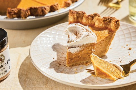 A slice of Smooth and Spicy Pumpkin Pie topped with whipped cream - select to zoom