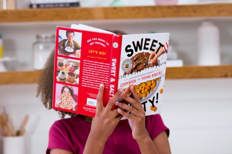 Kid holding up Sweet & Salty! kids' cookbook