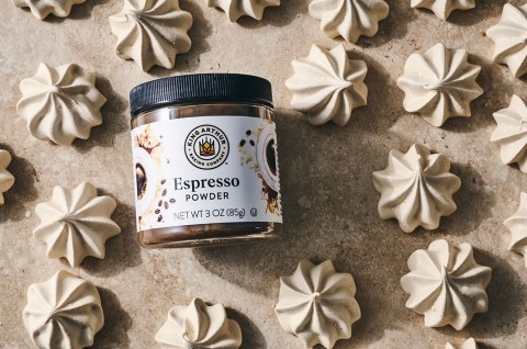Espresso Meringue powder from King Arthur Baking in laid on its side among many meringues spread on a neutral textured counter. - select to zoom