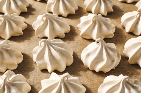 Several Espresso Meringues shown piped and baked on a neutral background with a swirling texture and curled tops. - select to zoom