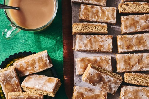 Lebkuchen on a sheet tray in half the photo and on the left side, lebkuchen is on a plate and there's a beverage in the corner. - select to zoom