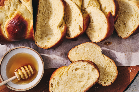 Challah bread sliced and shown on a counter with a bowl of honey next to the slices. - select to zoom