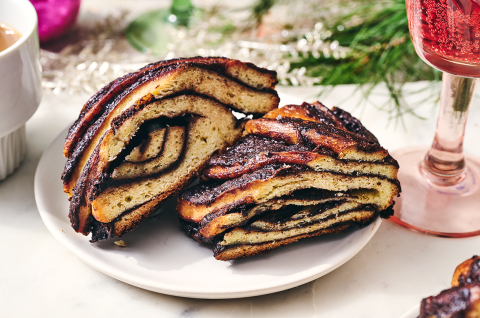 Two slices of chocolate babka wreath on a plate with festive ornamentation around the setting. - select to zoom