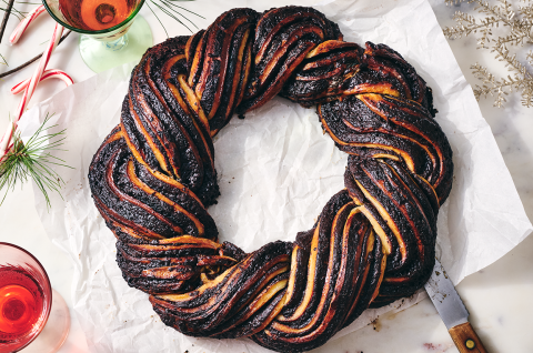 A full chocolate babka wreath on parchment paper on a countertop. - select to zoom
