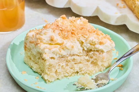 Creamy Coconut Sheet Cake on a plate with a small bite on a fork. - select to zoom
