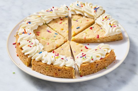 Confetti Sugar Cookie Cake sliced on a plate that's sitting on a marble countertop - select to zoom