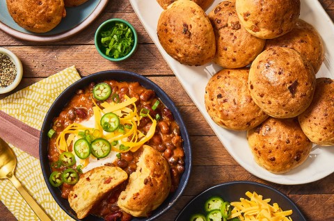 Gluten-Free Bacon Cheddar Rolls on a platter with a bowl of chili next to it. Seen from above. - select to zoom